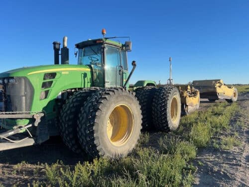 John Deere tractor in a field fitted with MDR 1000 tires and an attachment on the back. 